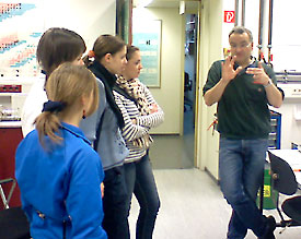 Prof. Stephan Schlemmer (r.) erkl&auml;rt Sch&uuml;lerinnen des 13er Physik-LKs, wie die Identifikation kosmischer Partikel funktioniert 